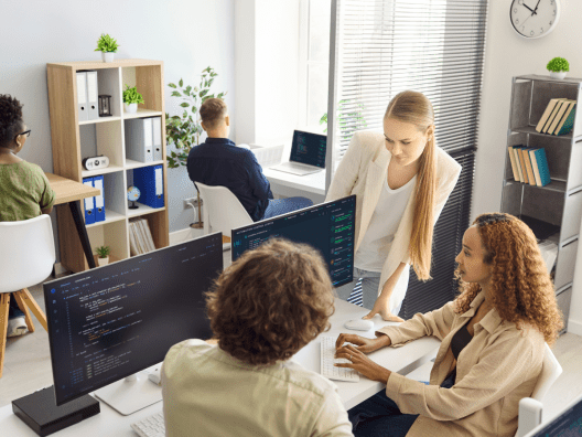 Team reviewing an automation control center dashboard on a monitor while a developer works on integration code